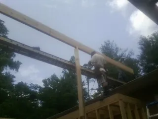 Carpenter setting a ridge beam over a new addition frame — Ice Dam Removal by Roofing Brothers in Jetson