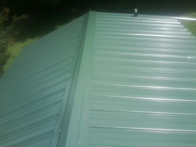 New green metal panels meeting at the ridge of a roof — Flat Roof Repair work by our crew in Jetson