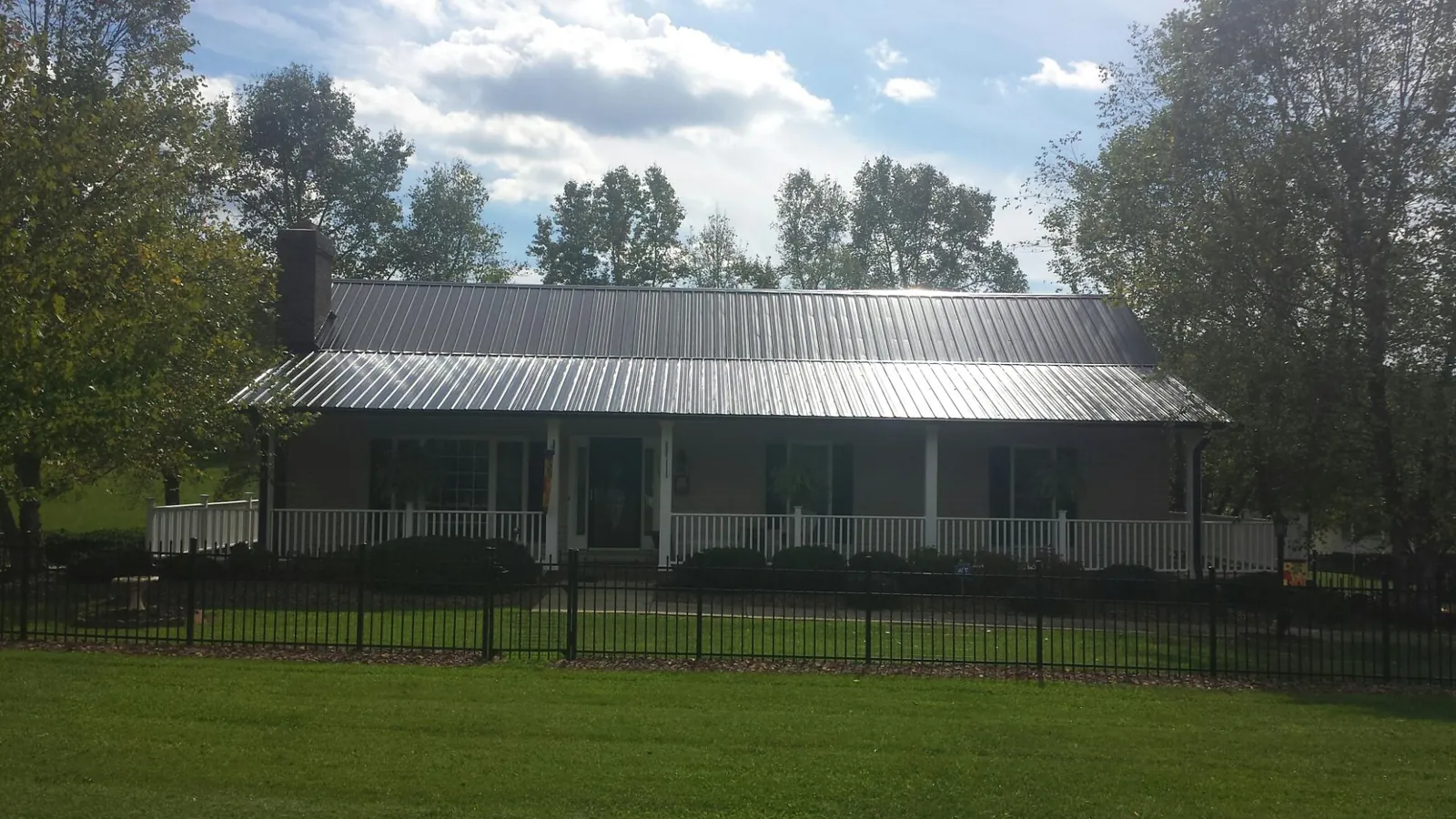Gray metal roof on a brick ranch with a full width front porch — Gutter Guard Installation work by our crew in Jetson