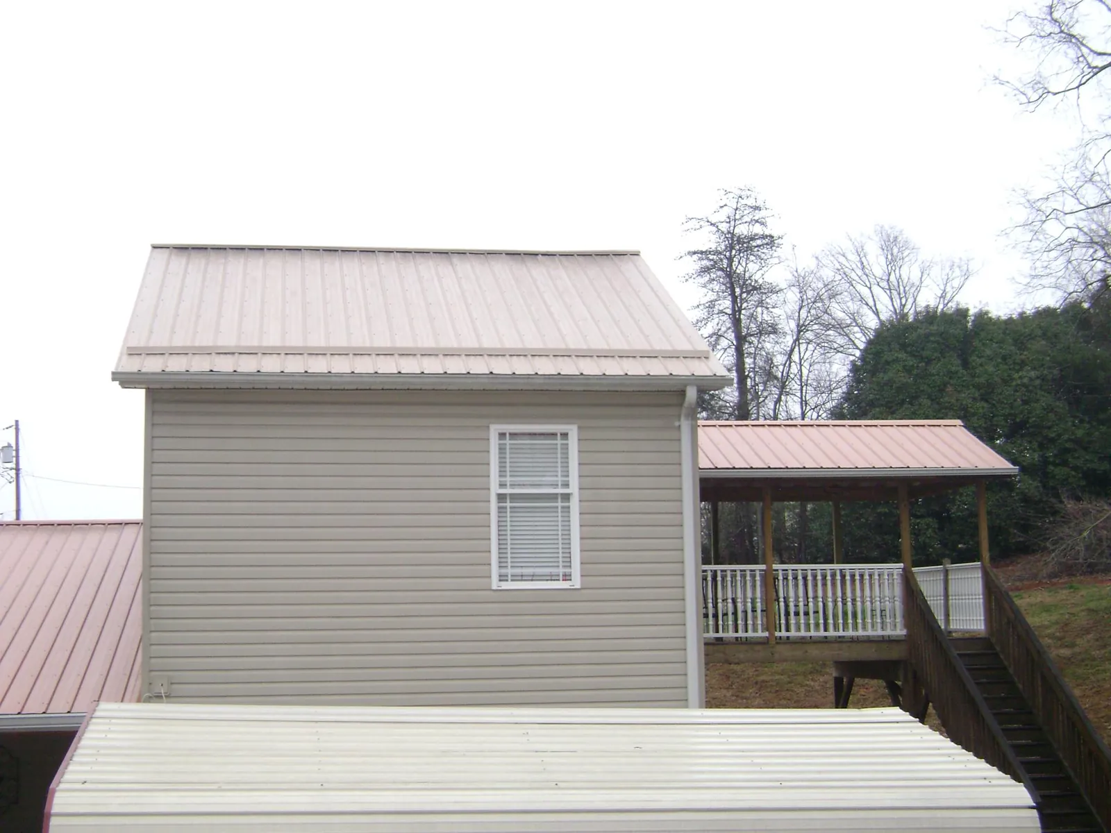 Tan metal roofs on a two story addition and attached porch, from a Roof Replacement job in Jetson