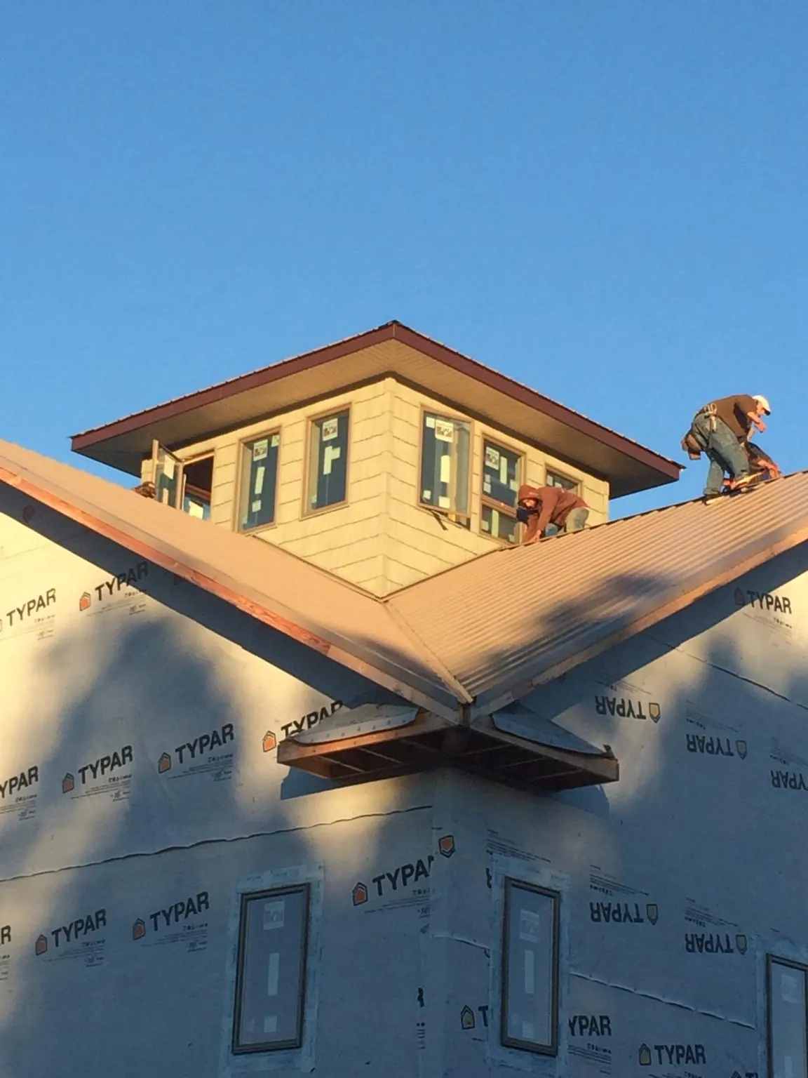 Roofers working around a rooftop cupola on a new metal roof at sunset — Roof Waterproofing in Jetson by Roofing Brothers